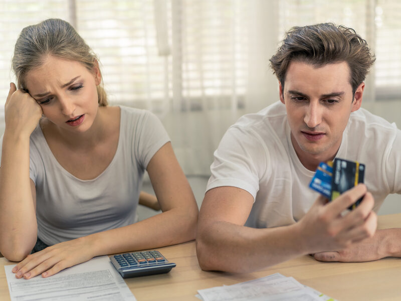 Couple at the kitchen table with bills, calculator, and a credit card — money fights couples therapy Los Angeles